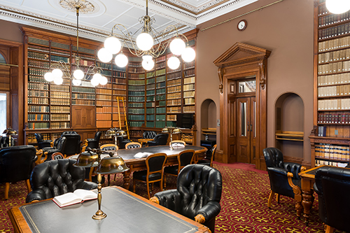 Members Reading Room - a large library lined with bookshelves full of books. In the center are tables with black leather chairs.